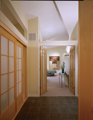 
A large rear foyer delineates the house’s private spaces, including the master suite. Japanese shoji screens just outside the bedroom enclose an office. This foyer can be conveniently accessed through the home’s back entrance, which leads to a garden room and garage. Ray bought the antique silk kimono, framed and displayed under museum-quality ­lighting, during a trip to Tokyo.
